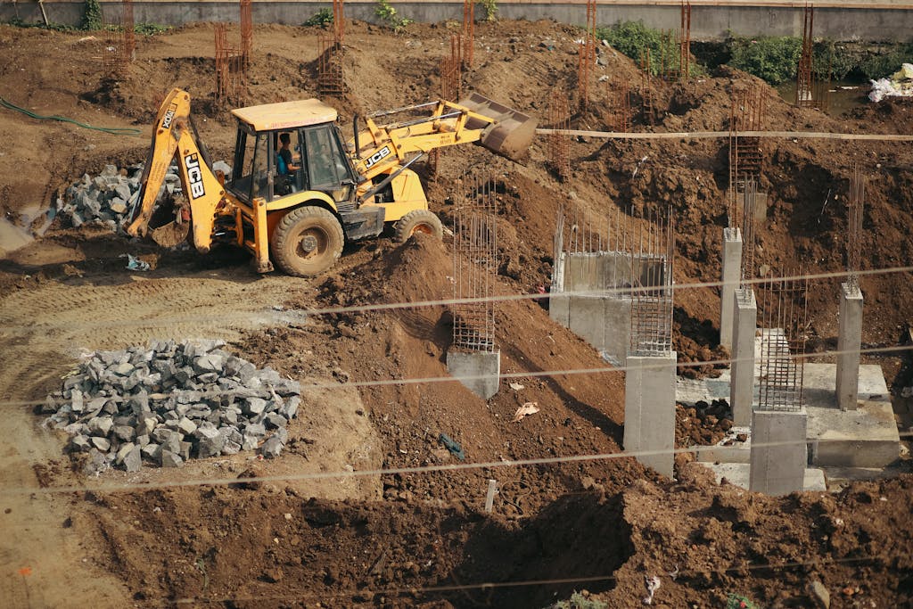 A bulldozer moves soil at a busy construction site, surrounded by piles of gravel and concrete structures.